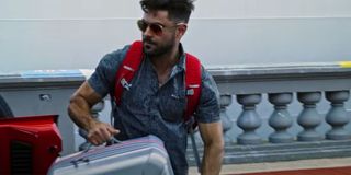 Efron lugging suitcase in Down to Earth Season 1 on Netflix