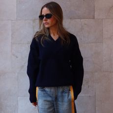 Nikki wears a navy sweater and miramar sport pants.
