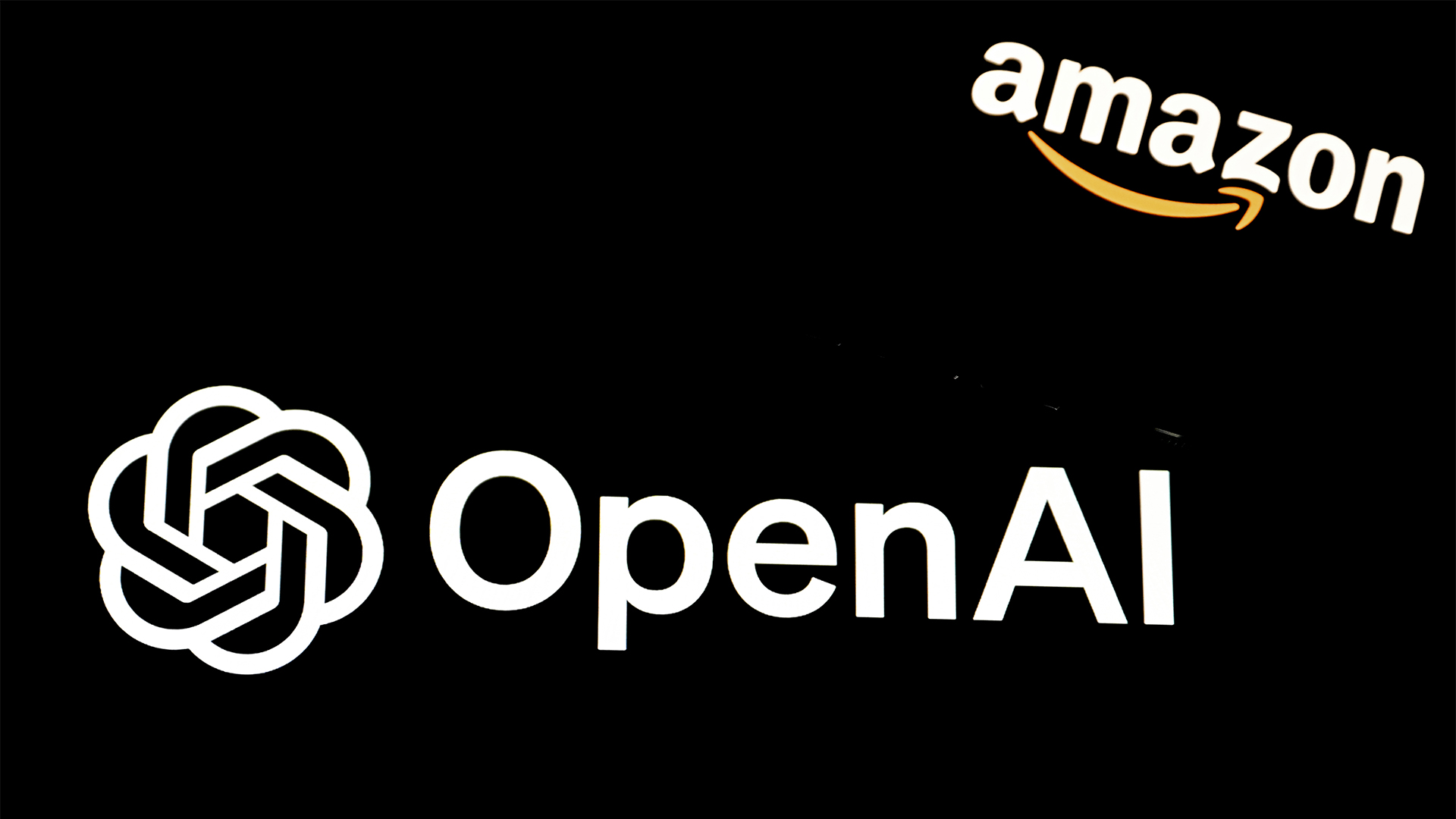 Amazon and OpenAI logos pictured against a black backdrop.
