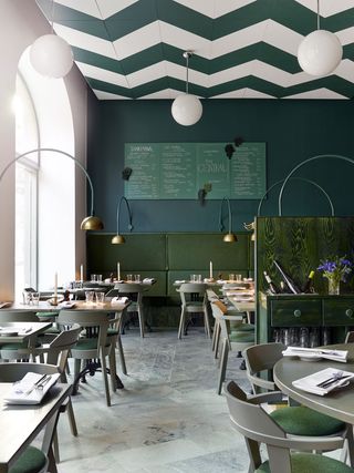Bar Central in Stockholm with green tables and chairs, green wall with menu written on chalkboard