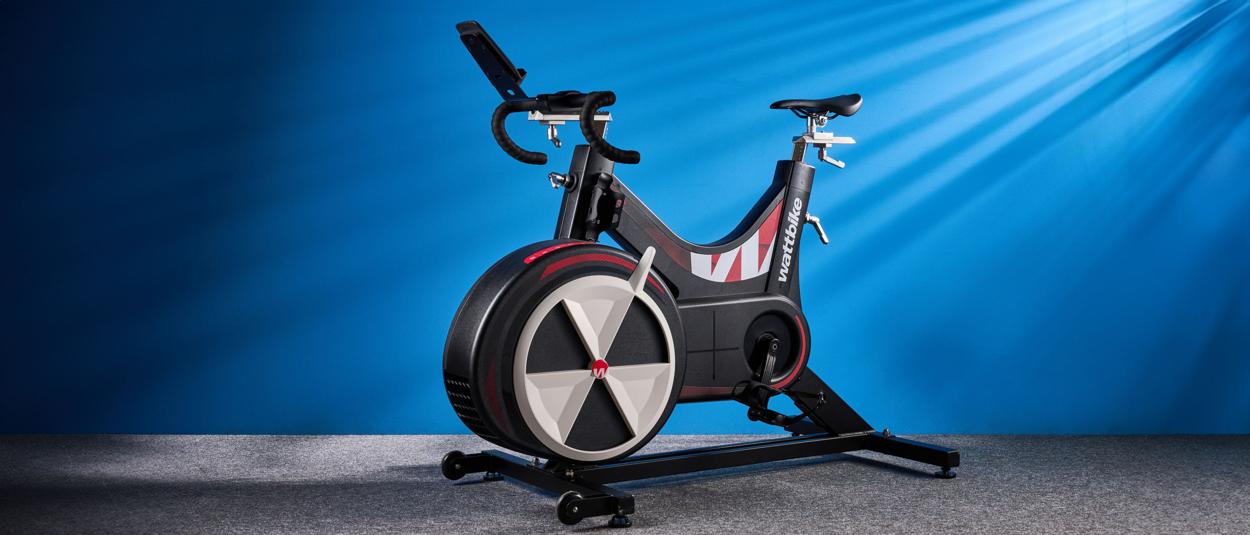 the wattbike air with a black and white front wheel, adjustable seat, and phone holder with app compatibility