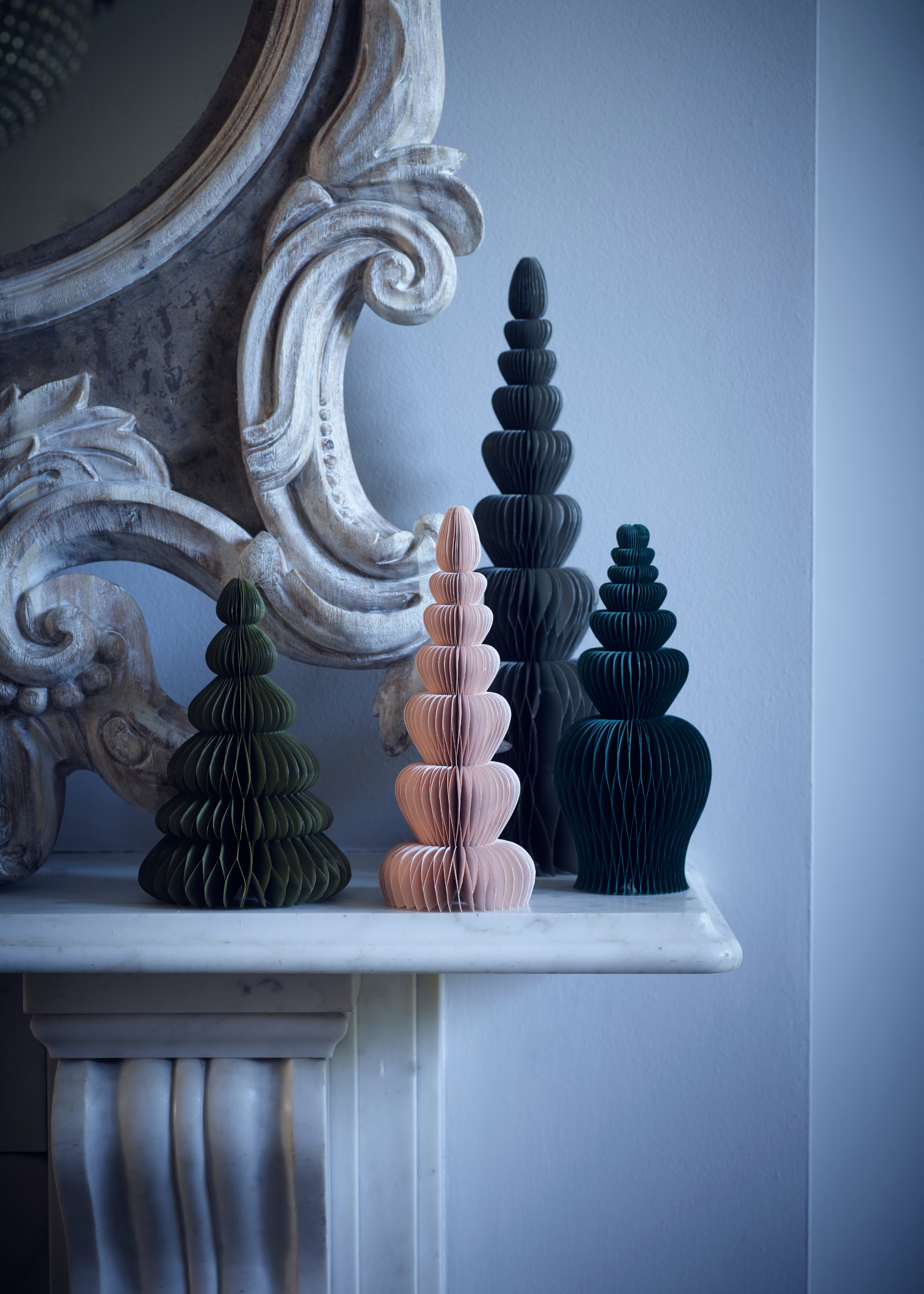 A cream mantelpiece is adorned with a collection of different colored and sized paper decorations