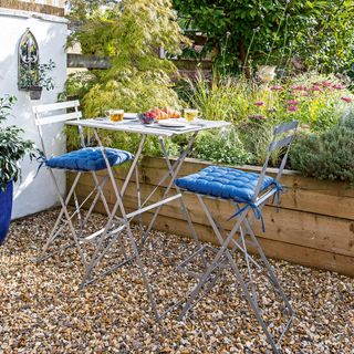 Gravel terrace area with bistro set and raised beds behind