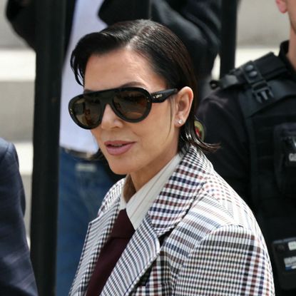 a woman with short dark hair wearing a printed suit in a paparazzi photo