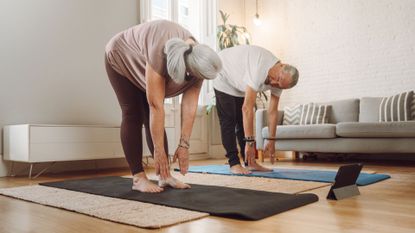 senior couple touch toes on yoga mats
