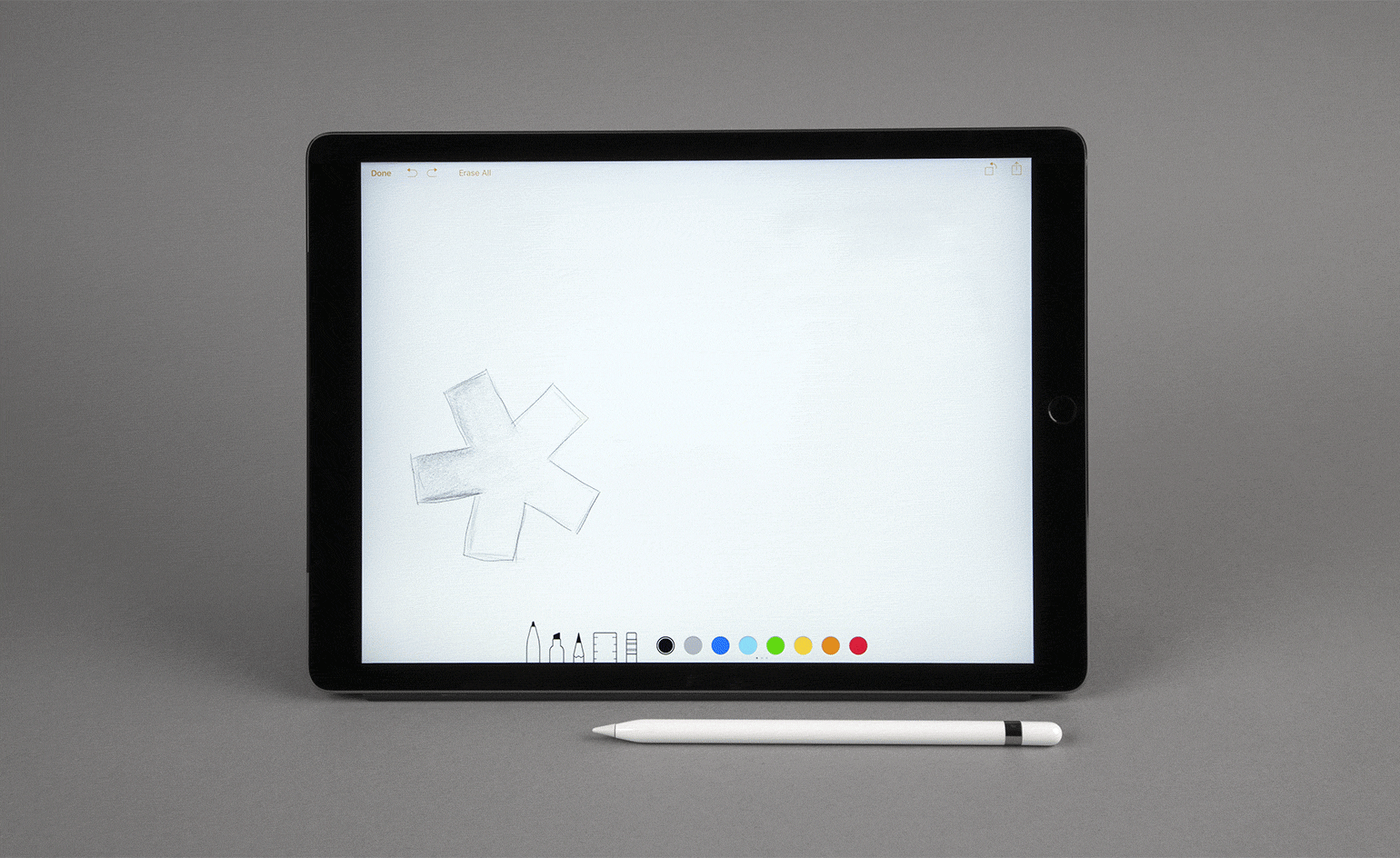 Gif of an Apple Pencil in front of an Apple iPad with the Wallpaper* asterisk appearing on the screen in different colours - both items are pictured against a grey background