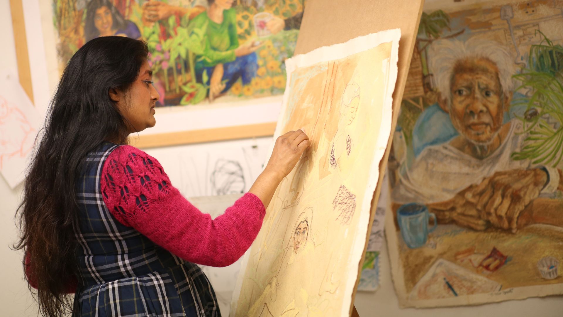 an image of an artist paintig and sketching on a piece on an easel in the middle of one of the studio galleries