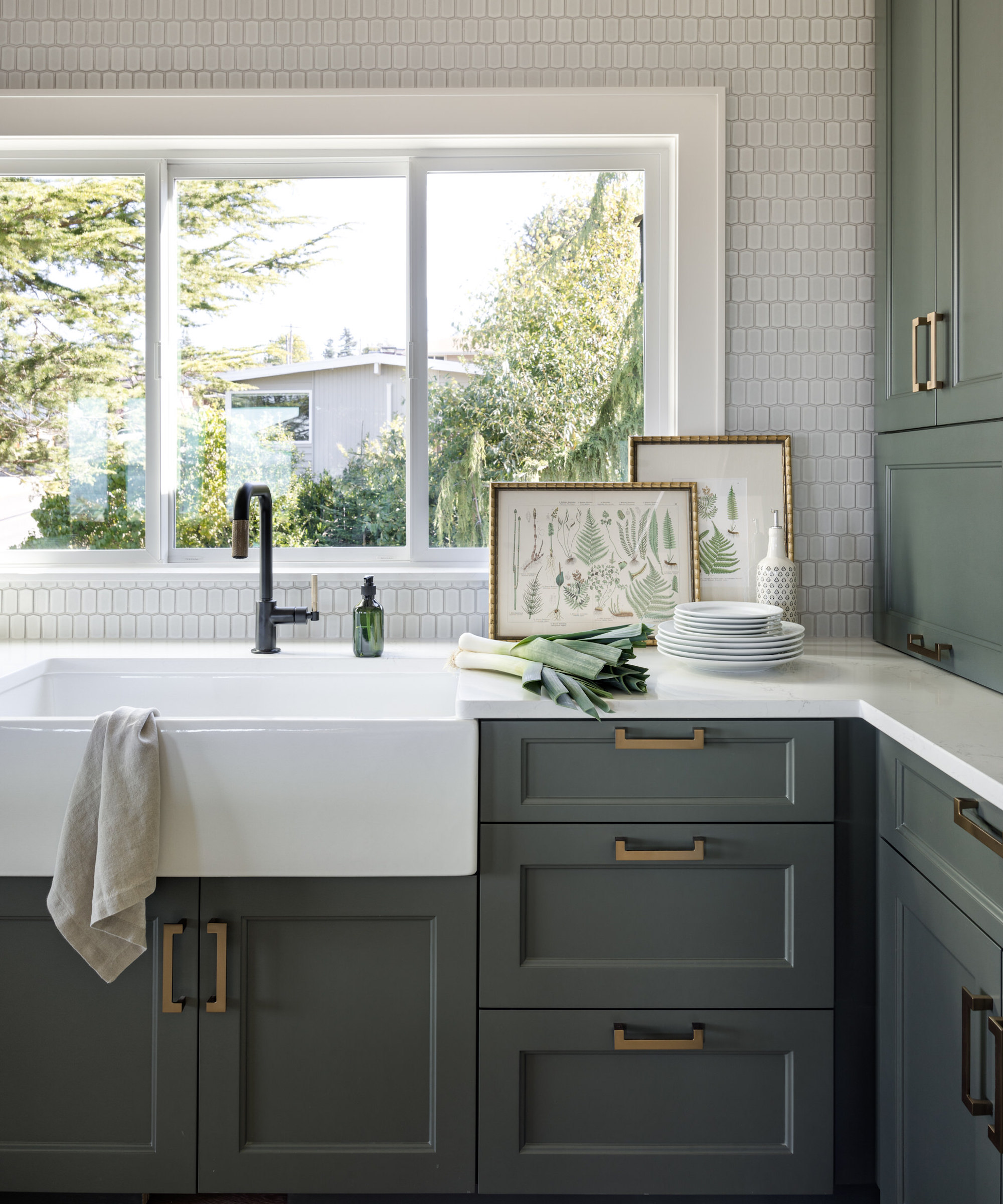Detail of kitchen with green cabinets, butler sink and black faucet