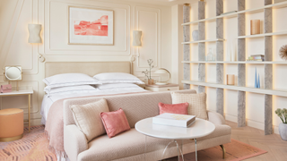 A bedroom at One Aldwych, with sofa, coffee table and double bed, in pastel pink hues