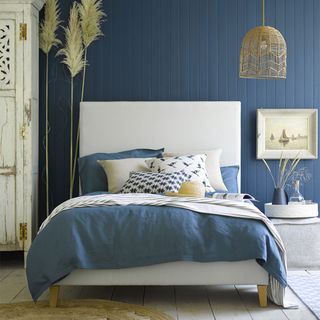 Blue bedroom with blue panelled walls and denim bedlinen