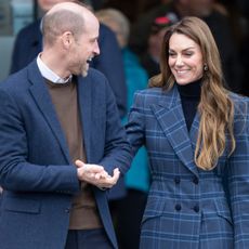 Prince William and Princess Kate wearing blue jackets and laughing