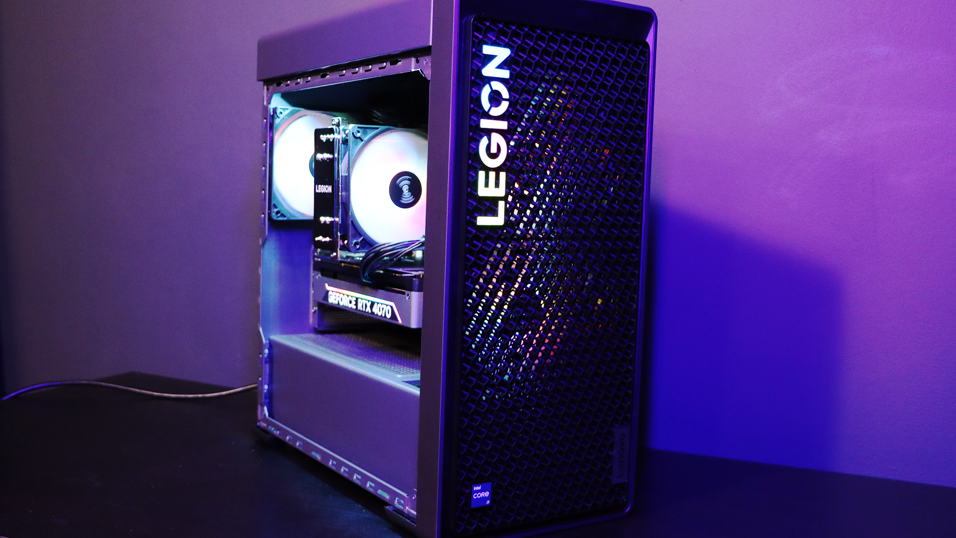 Üzerinde mor ışık bulunan bir masanın üzerindeki Lenovo Legion Tower 5i PC