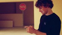 Kane Parsons on set of Backrooms, with a reversed stop sign in the background, a delicious foil for the headline which says he is not stopping making Backrooms stuff