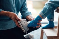 A parent putting on their child's shoes for them.