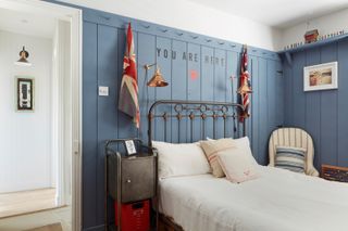bedroom with iron bedframe and blue panelled room