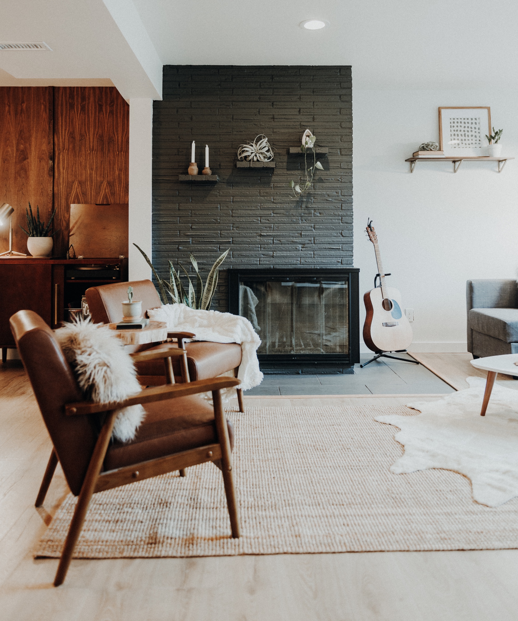 Black fireplace against black accent wall in modern living room with leather and wooden seats