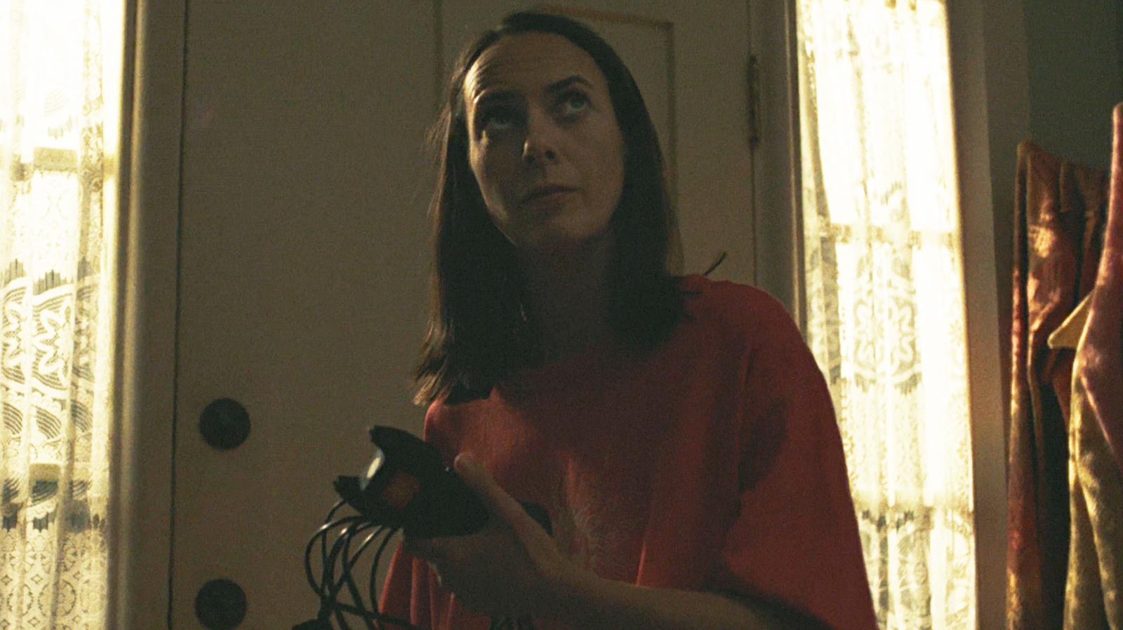 Patricia holding a tazer and its charging cable in her house at night in Widow's Bay episode 8