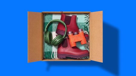 A shipping box filled with assorted products, including headphones, binoculars and boots.