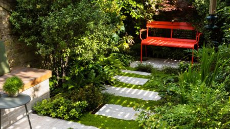 a garden patio with mind your business and ferns and a bright red garden bench