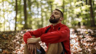 Man meditating outside in forest