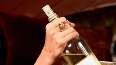 woman with bracelets removing wine from bucket