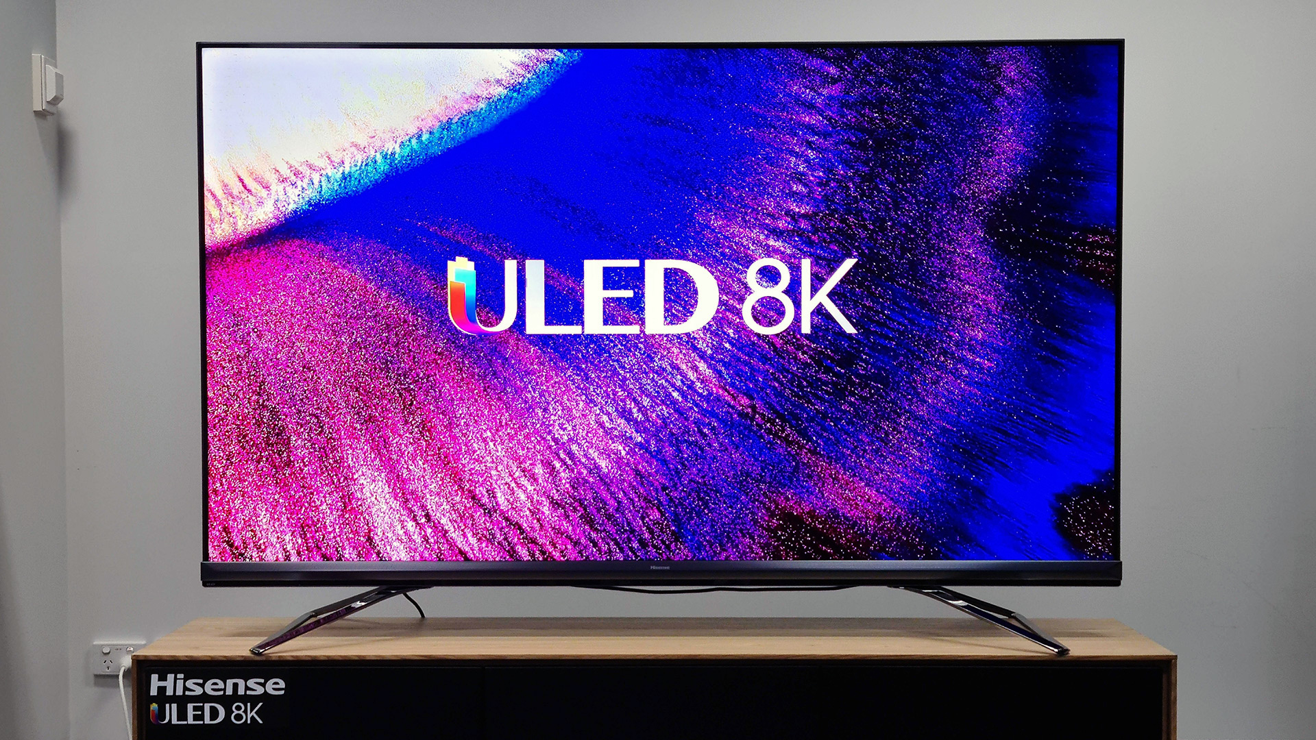 The Hisense U80G 8K ULED TV with a bright screen and abstract pink and purple display