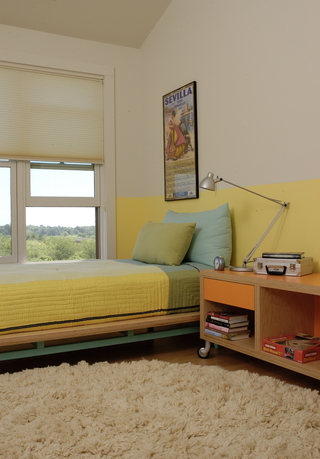 A bedroom with a half-painted yellow wall, and yellow bedding