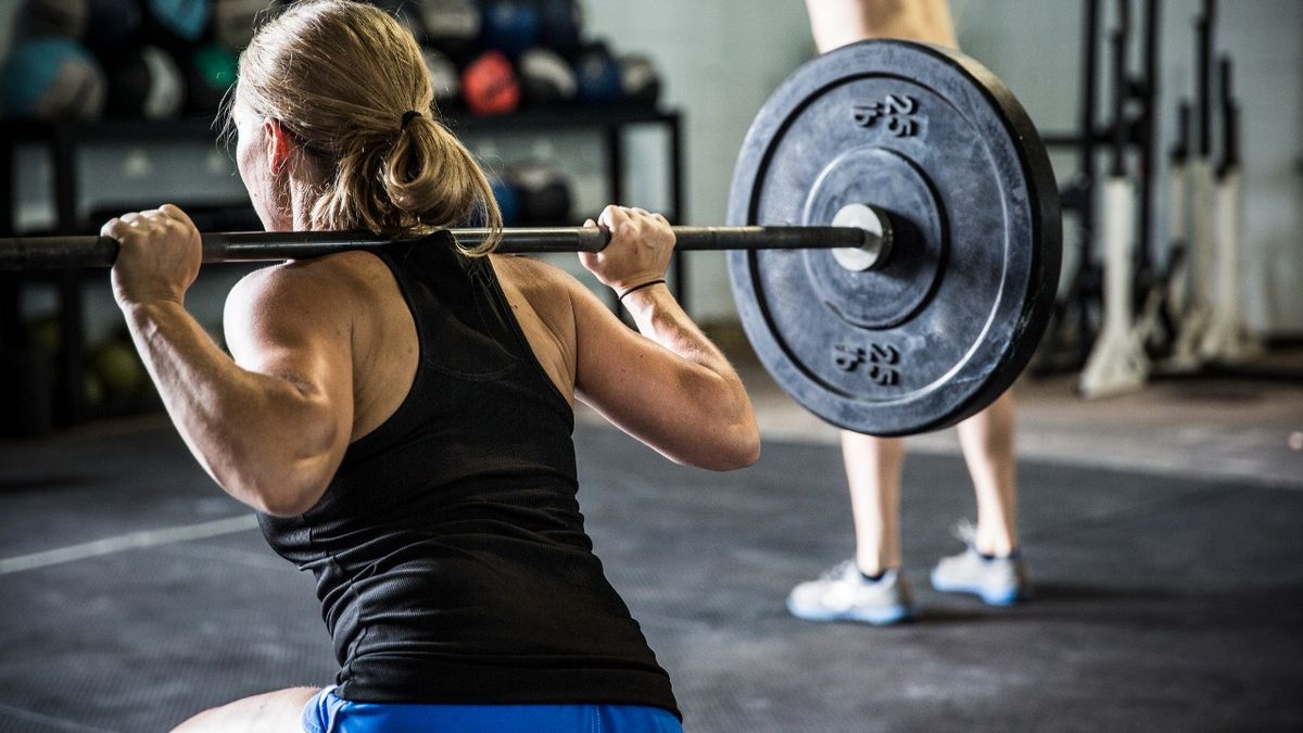 Woman performs barbell squat