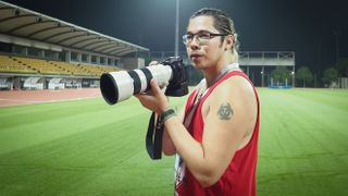 Photographer James Artaius using the Sony A9 III with Sony 300mm lens, standing in a floodlit track and field stadium at night