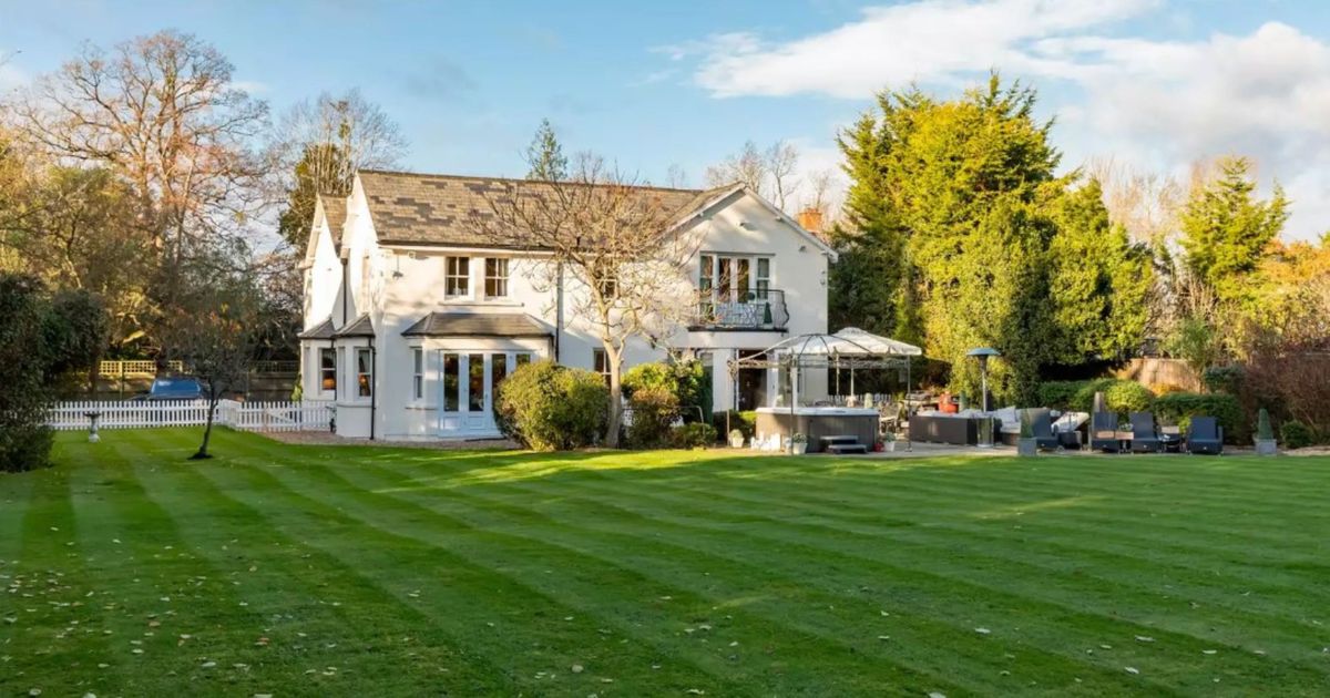 The view of the house from the garden shows the patio and large garden with a the white two-storey house in the background