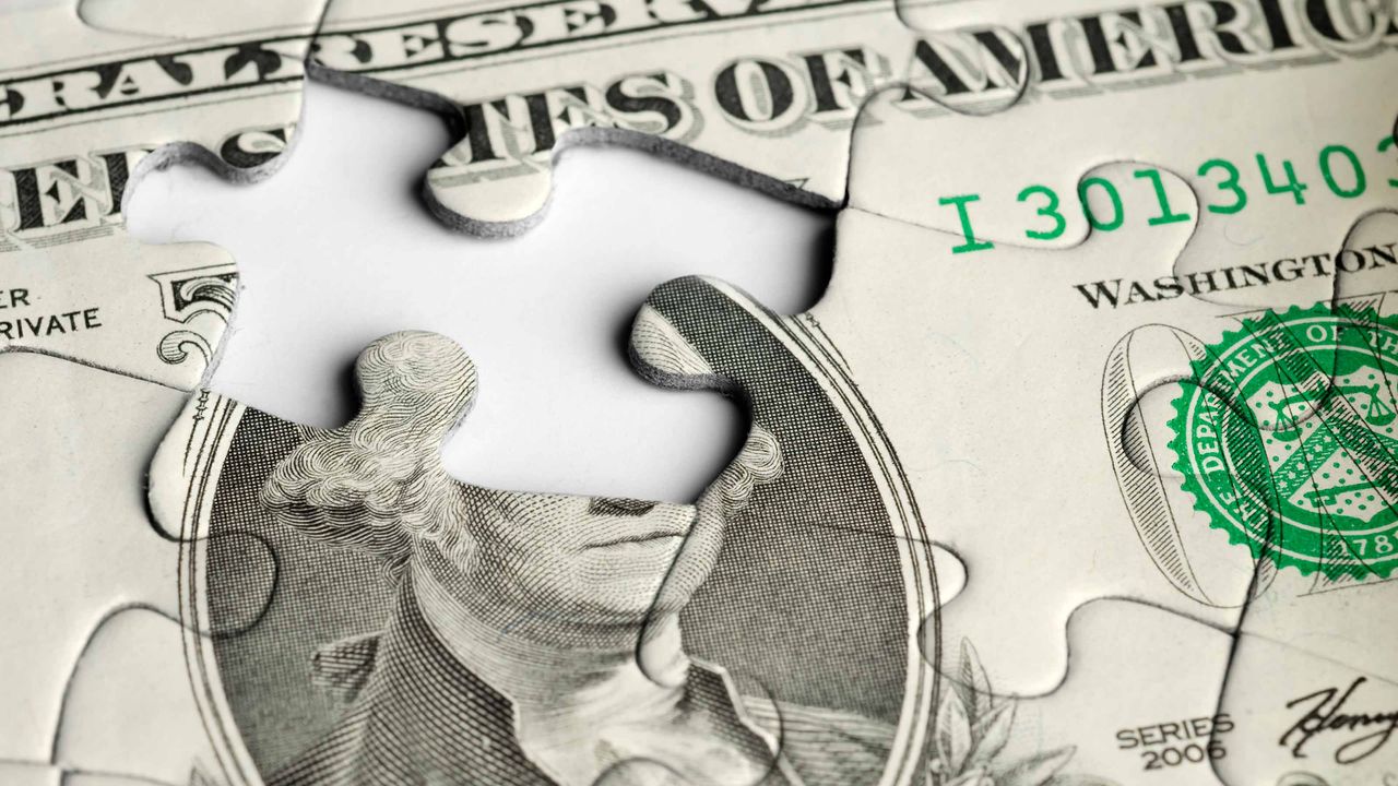 A puzzle of a dollar bill has a missing piece.