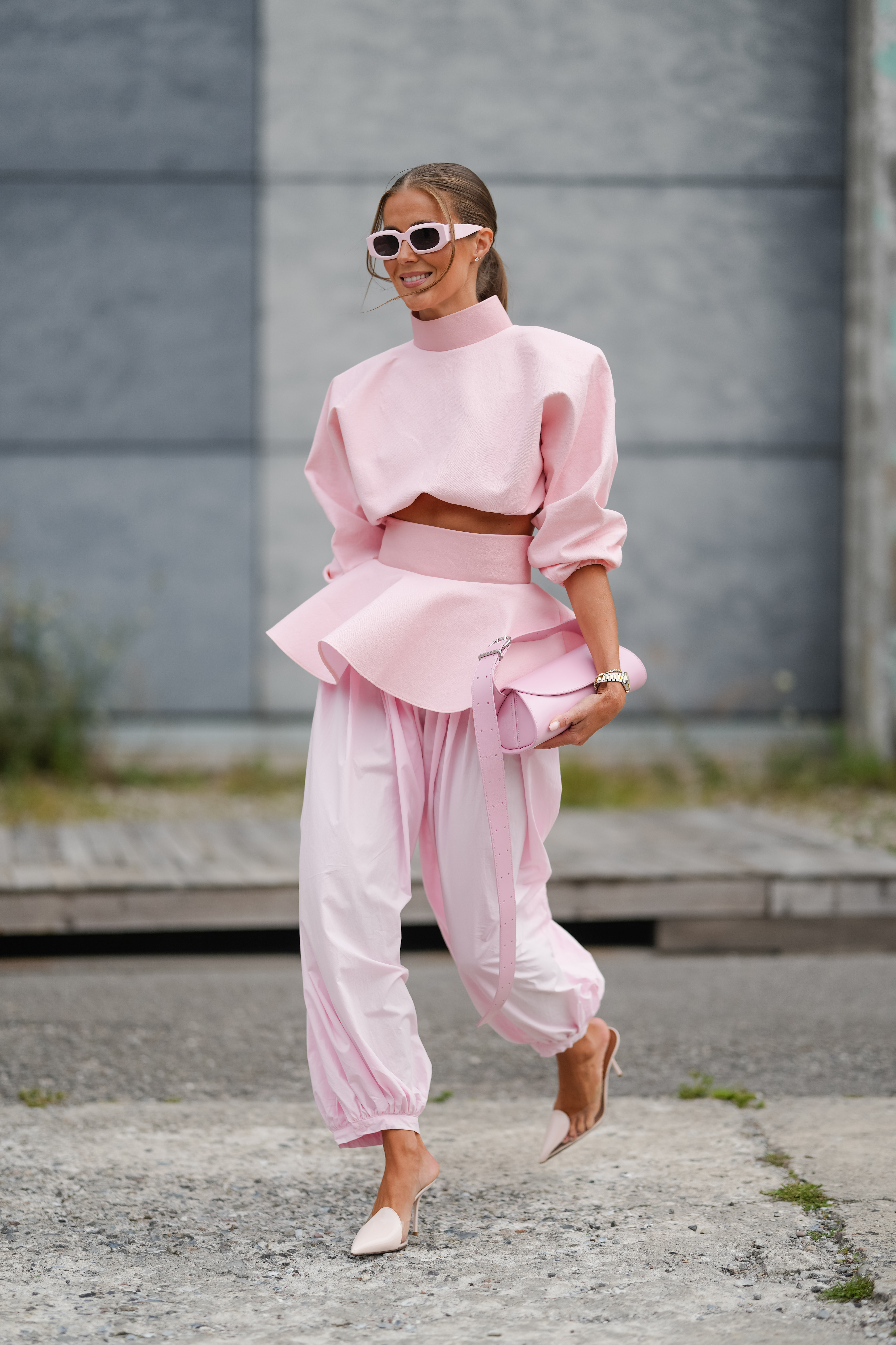 A fashion person spotted in Copenhagen wears the pale pink trouser trend. She paired her trousers with a matching pink top, clutch and Alaïa heels in a recent image taken from Getty.