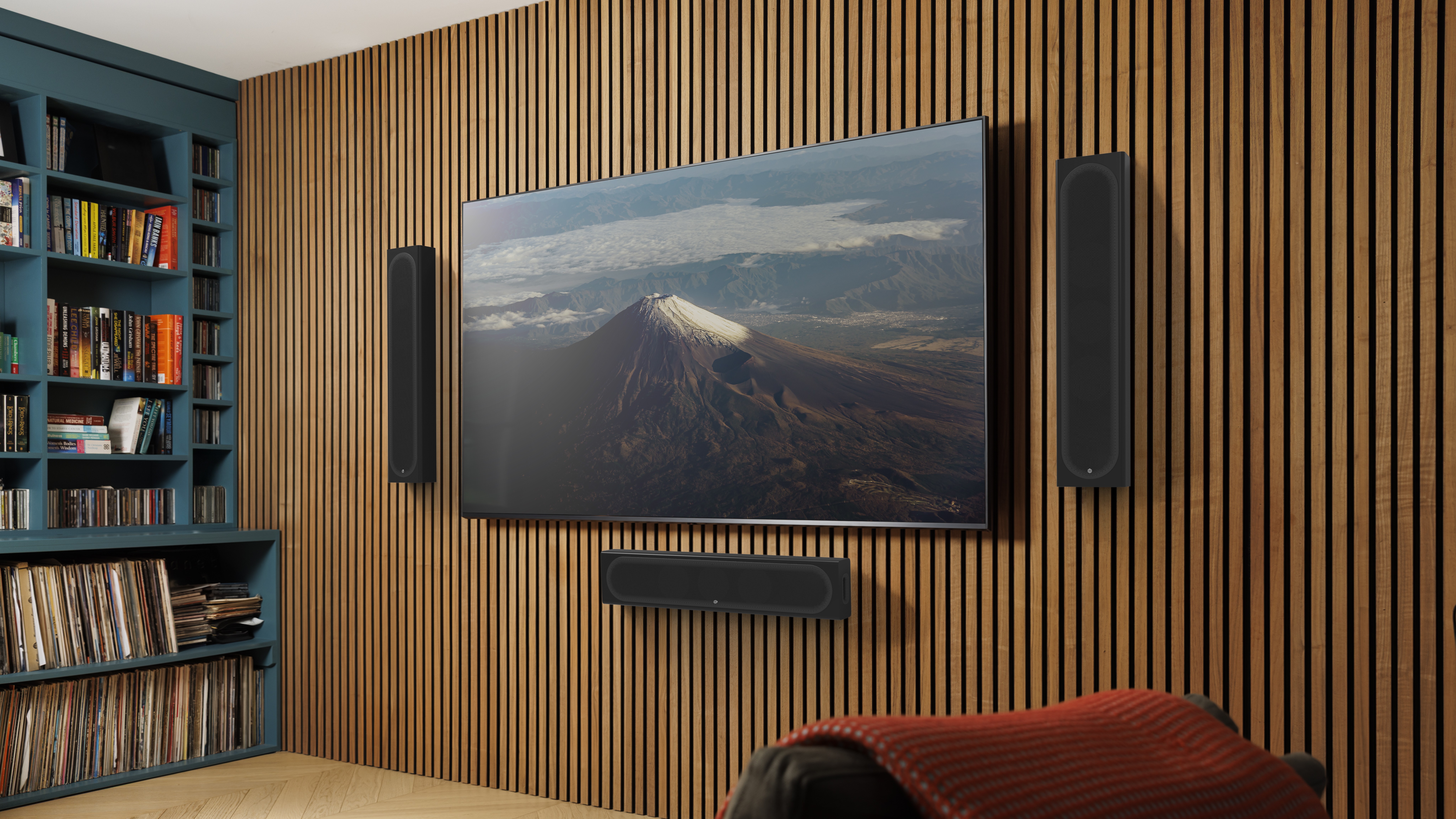 Monitor Audio Radius Series 4G On-Wall, next to a wall-mounted TV.
