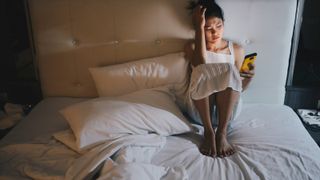 Woman scrolling on smartphone in bed