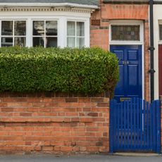 A blue front door with a matching front gate on a red brick house