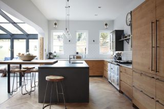 industrial style kitchen with black and wood units and central island by fritz fryer