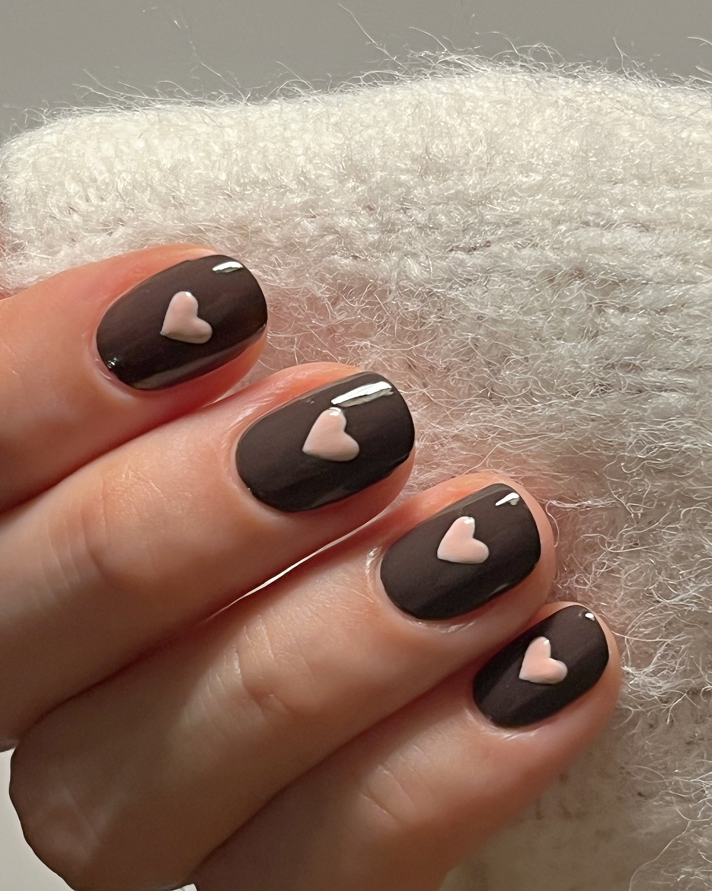 A brown manicure with pink hearts on top