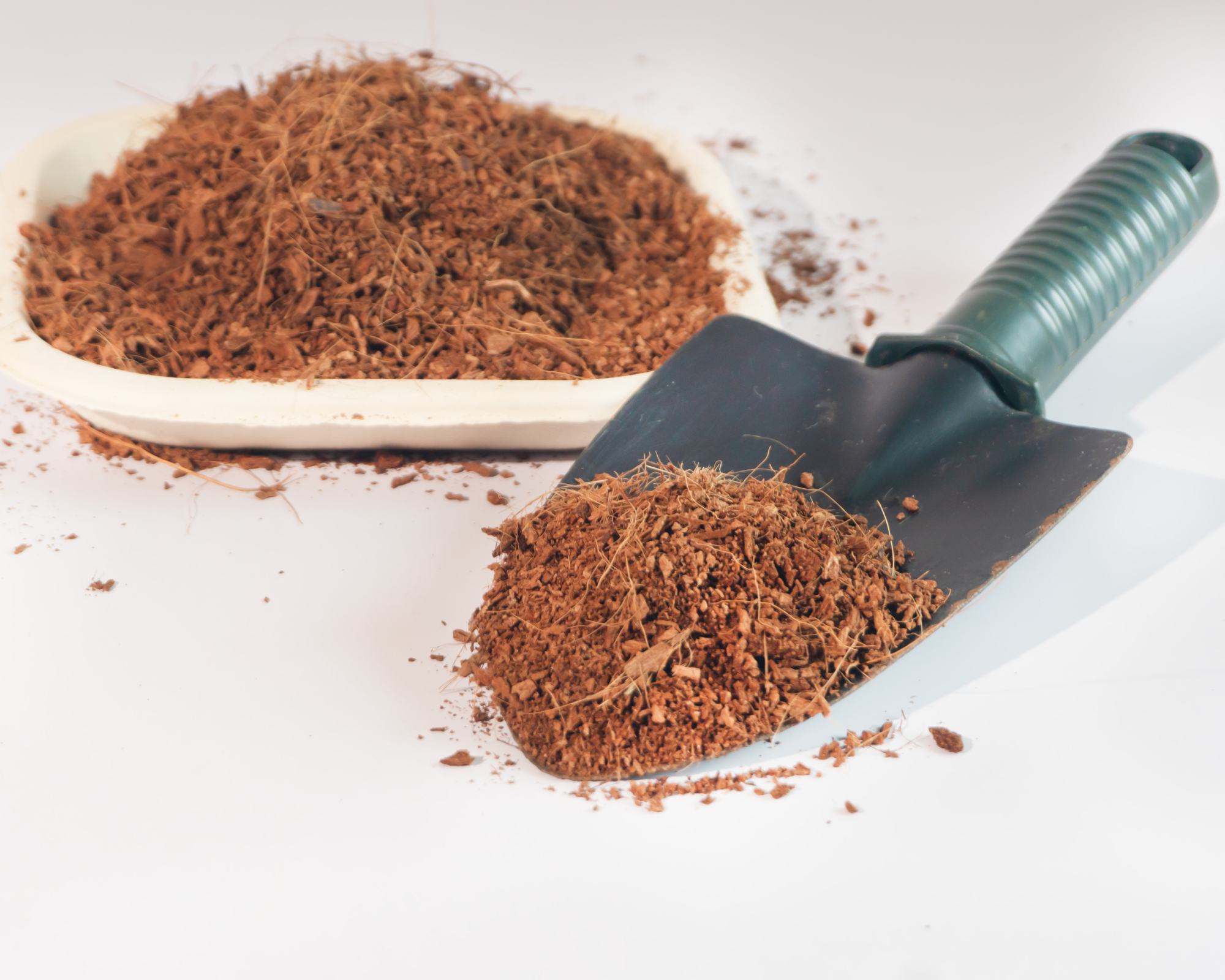a trowel loaded with coconut coir to improve moisture control in a garden container