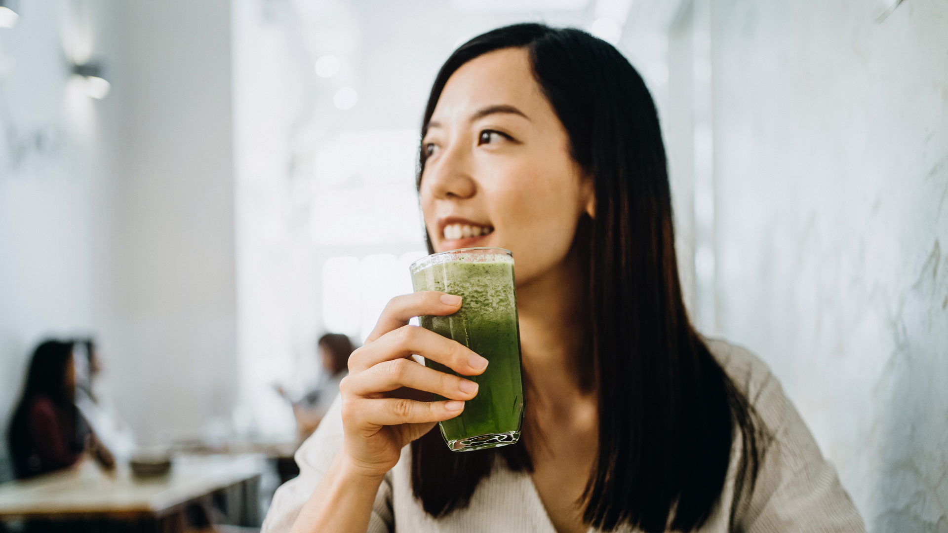 woman drinking a green vegetable smoothie