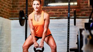 Woman performs deadlift with kettlebell