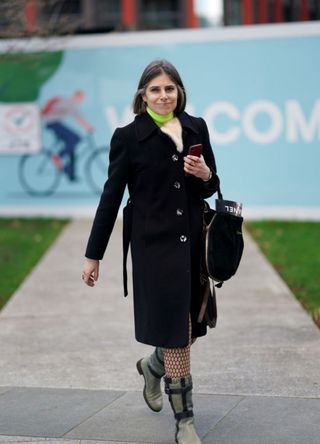 Woman wearing a long black coat and fishnets in London