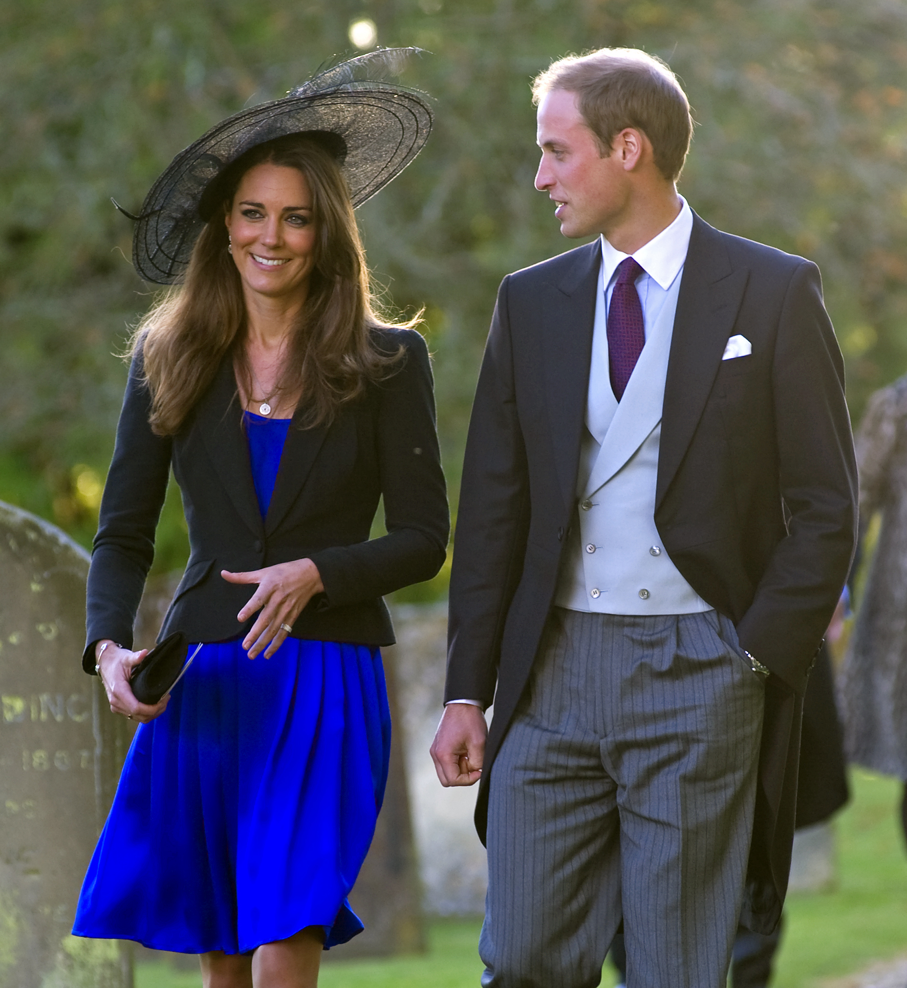 Kate Middleton wears a royal blue dress and a black jacket and hat while attending a wedding with Prince William in October 2010