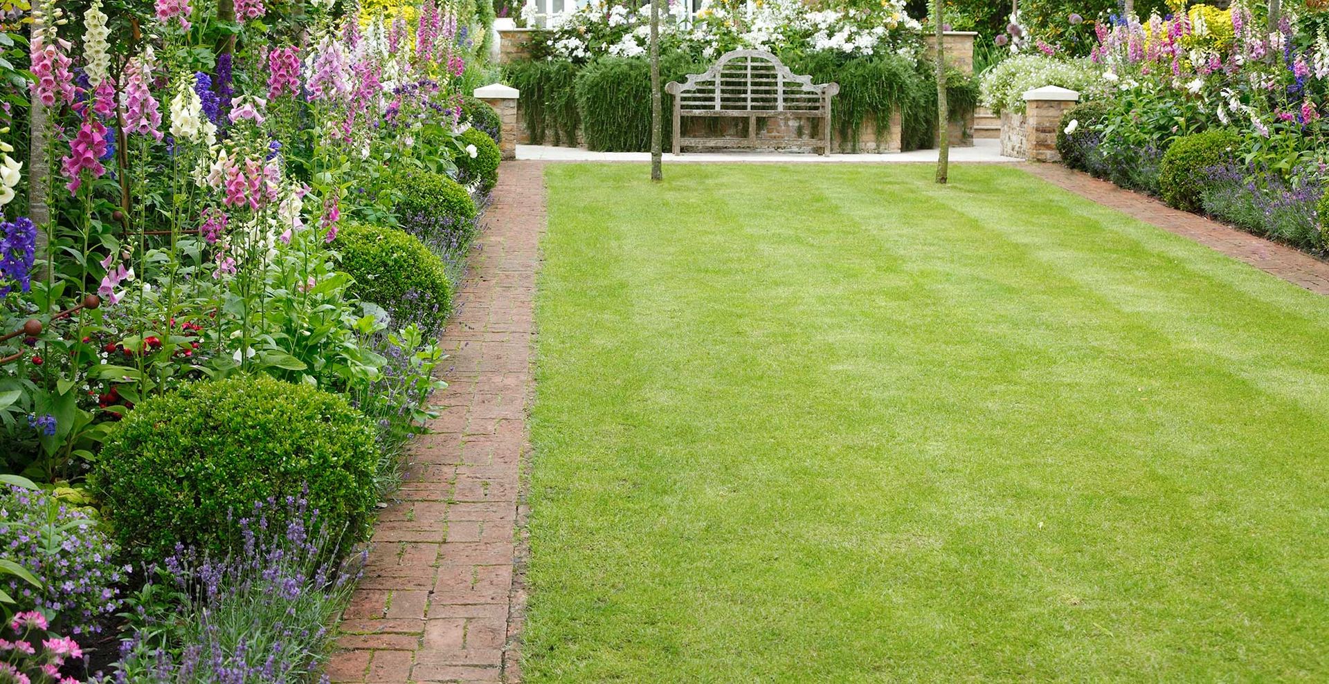 Backyard with lawn and flower borders to support a guide for how to get rid of weeds in grass