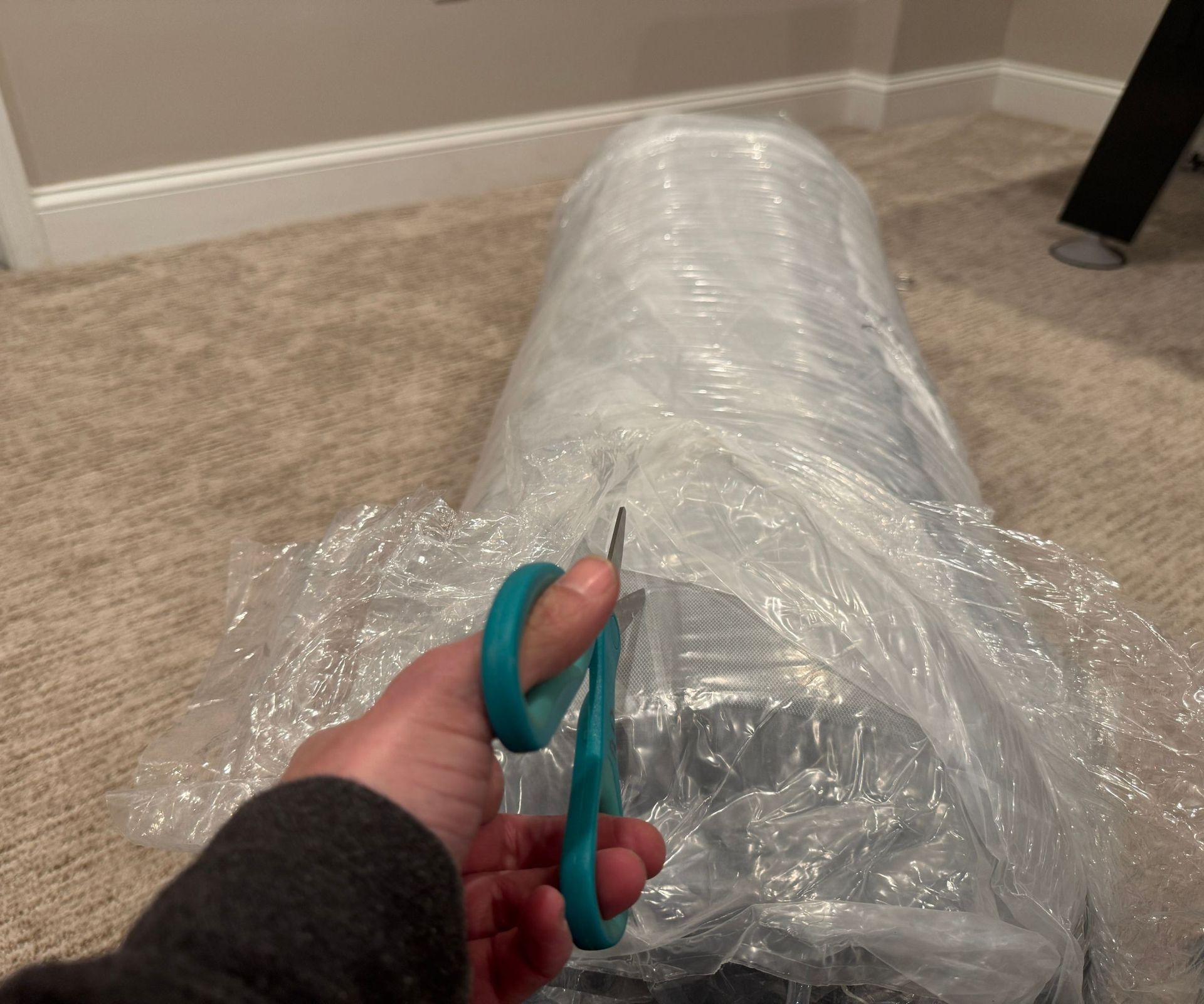Cutting the plastic on the TEMPUR-Cloud on a beige carpet.