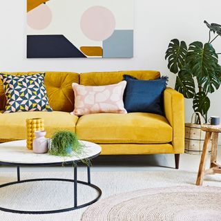 Living room with ochre sofa, layered rugs and round coffee table