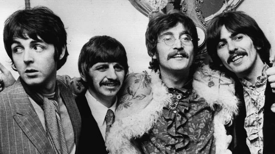 The Beatles standing with their arms around each other&#039;s shoulders in 1967