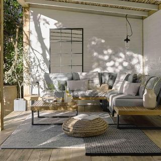 outdoor living room with coffee table and sofa with cushions and rugs with pouffe