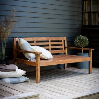 Garden Trading's Chastleton teak garden bench on a wood porch