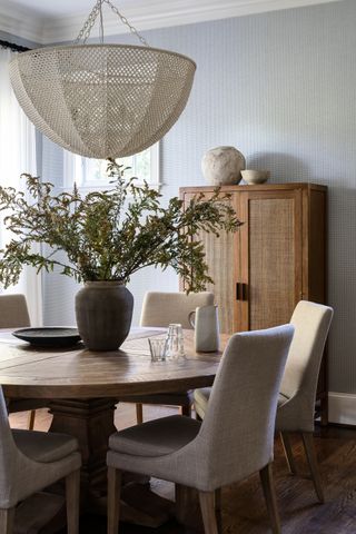 A breakfast room with a round table and a large wicker pedant shade