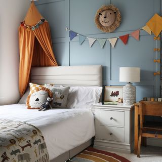 a toddler's bedroom with blue panelled walls, colourful bunting, bed tent and animal motifs